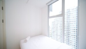 A small, white room with a single bed and a large window. - Compact And Homey 2Br At Benson Supermall Mansion Apartment (Surabaya)