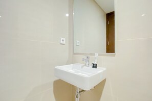 Ein Badezimmer mit einem weißen Waschbecken, einem Spiegel und beige gestrichenen Wänden.