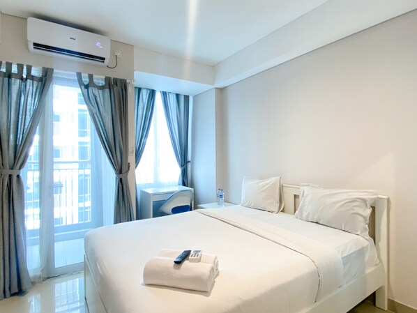 Relax in a spacious room with a large bed, bedside table, and balcony access.