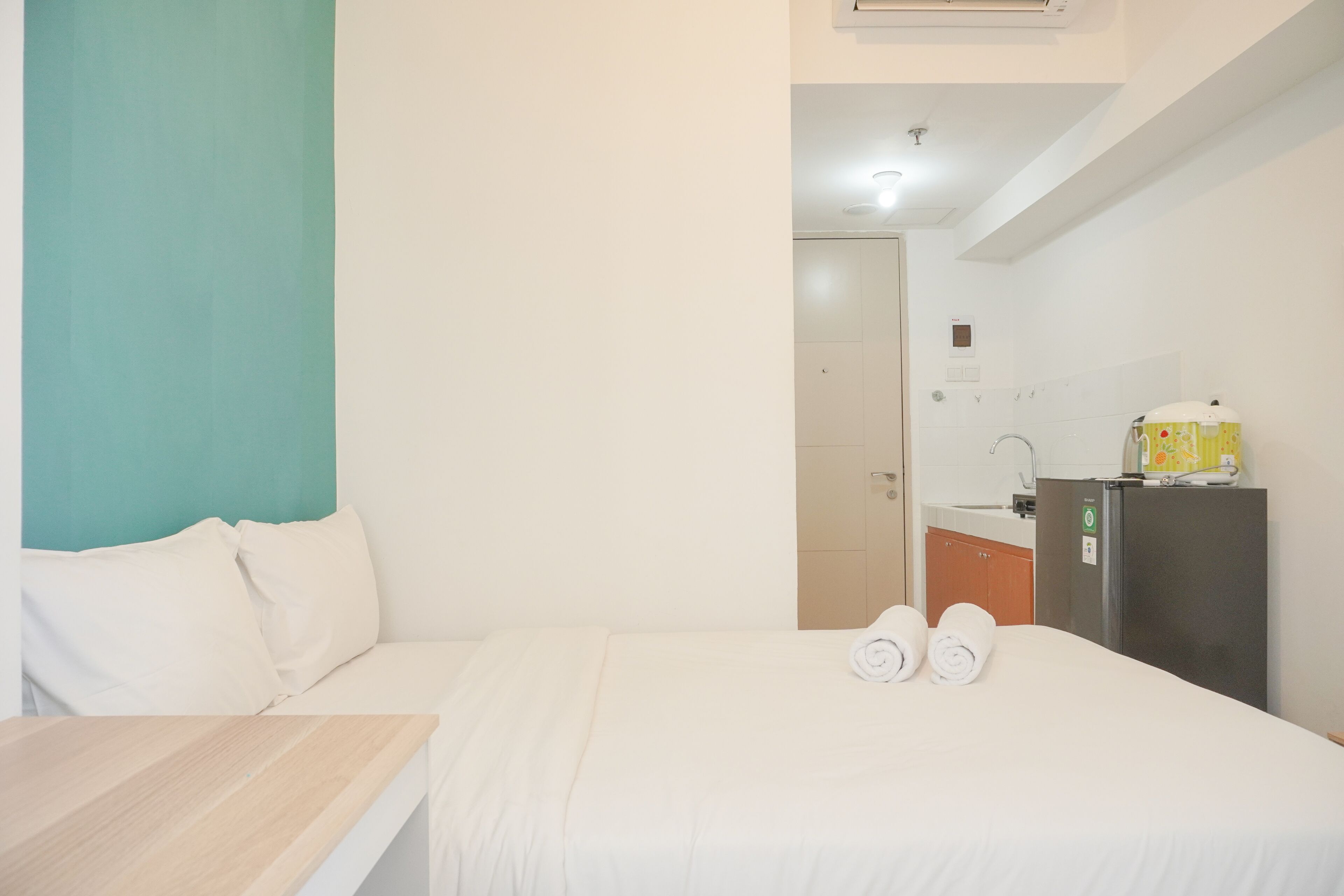 Ein Hotelzimmer mit einem Bett, einem Holztisch, einer Küchenzeile und einem durch eine offene Tür einsehbaren Badezimmer.