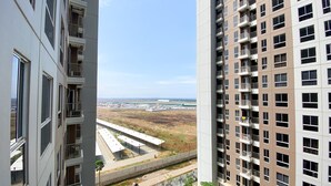 A high-rise building with multiple balconies and a view of a parking area and distant buildings. - Fully Furnished Studio At 11Th Floor Tokyo Riverside Pik 2 Apartment (Teluknaga)