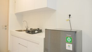 Uma cozinha com geladeira de aço inoxidável, fogão a gás e bancada branca.