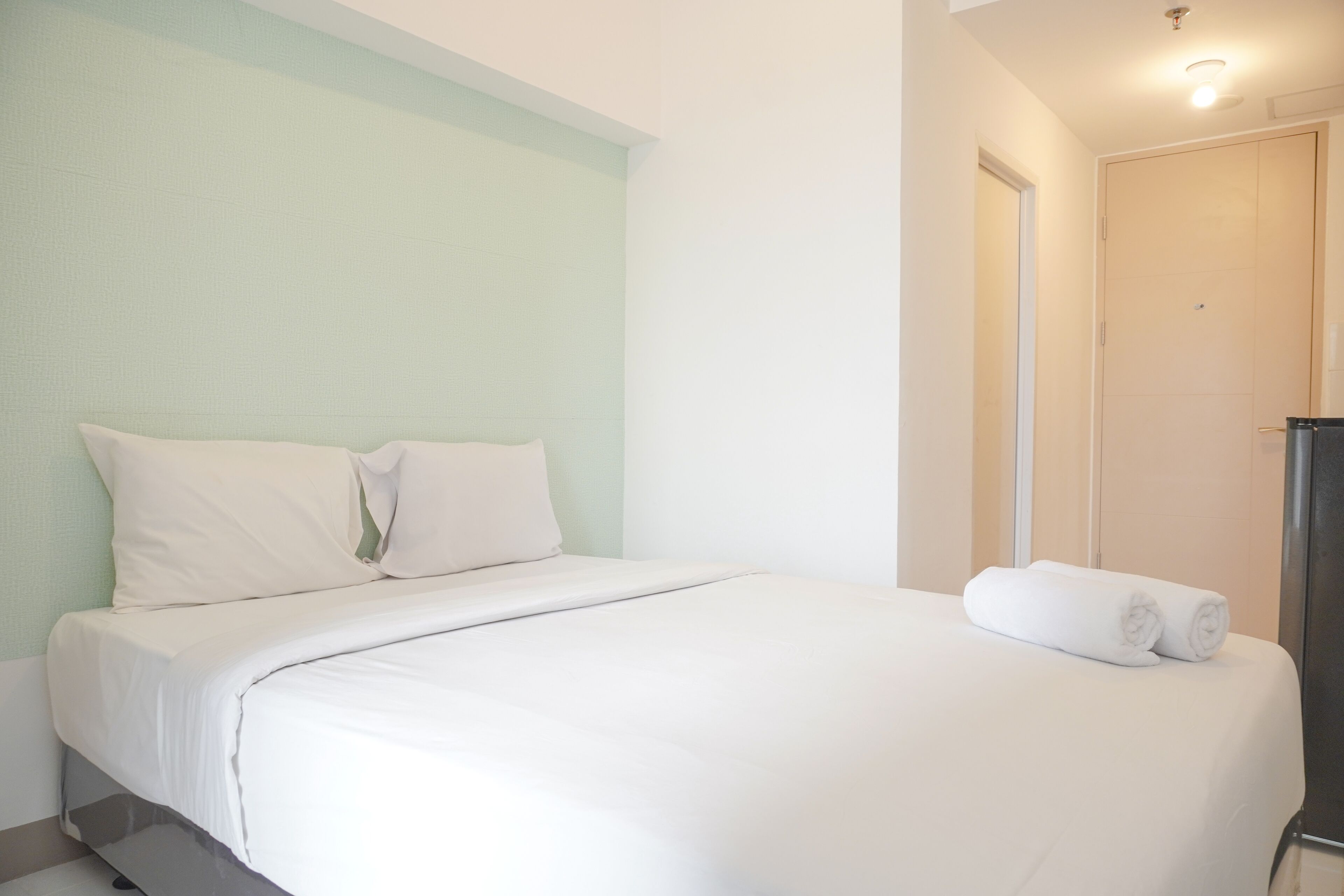 Una habitación de hotel con una cama, una puerta y una toalla sobre la cama.