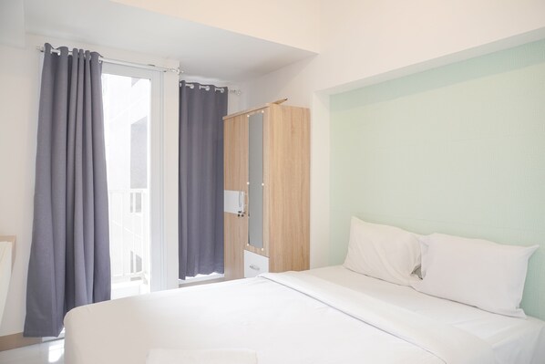 A bedroom with a bed, a wardrobe, and a window with curtains.