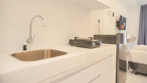 Uma cozinha moderna com uma pia de aço inoxidável, fogão embutido e geladeira.