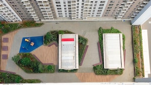 Vista aérea de un complejo residencial con varios edificios, zonas verdes y un parque infantil.