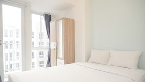 Habitación de hotel con una cama grande, un armario de madera y un gran ventanal corredero que da a un balcón.