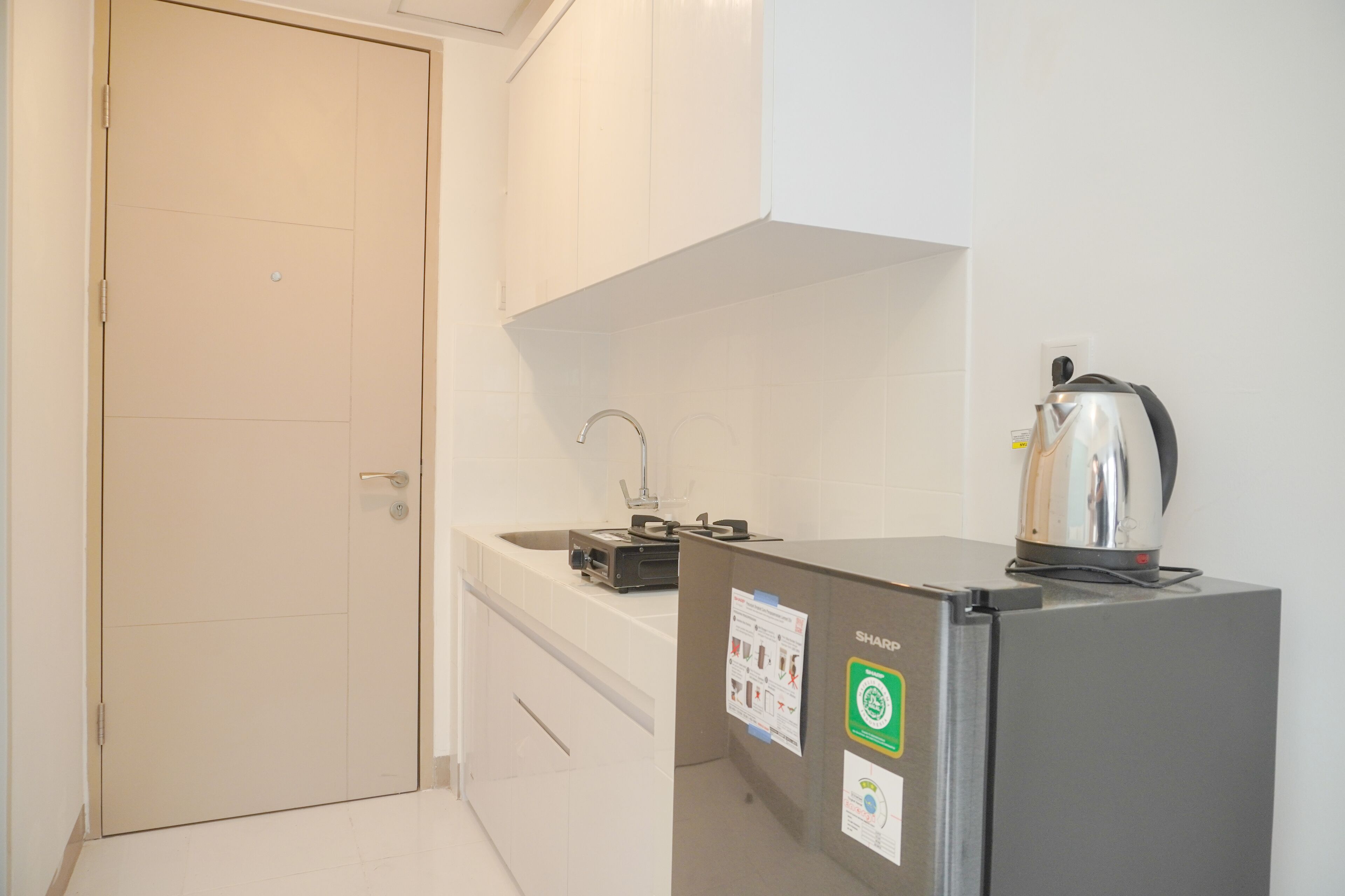 A small kitchenette with a refrigerator, a kettle, and a sink.