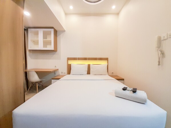 A hotel room with a bed, a desk, and a chair.