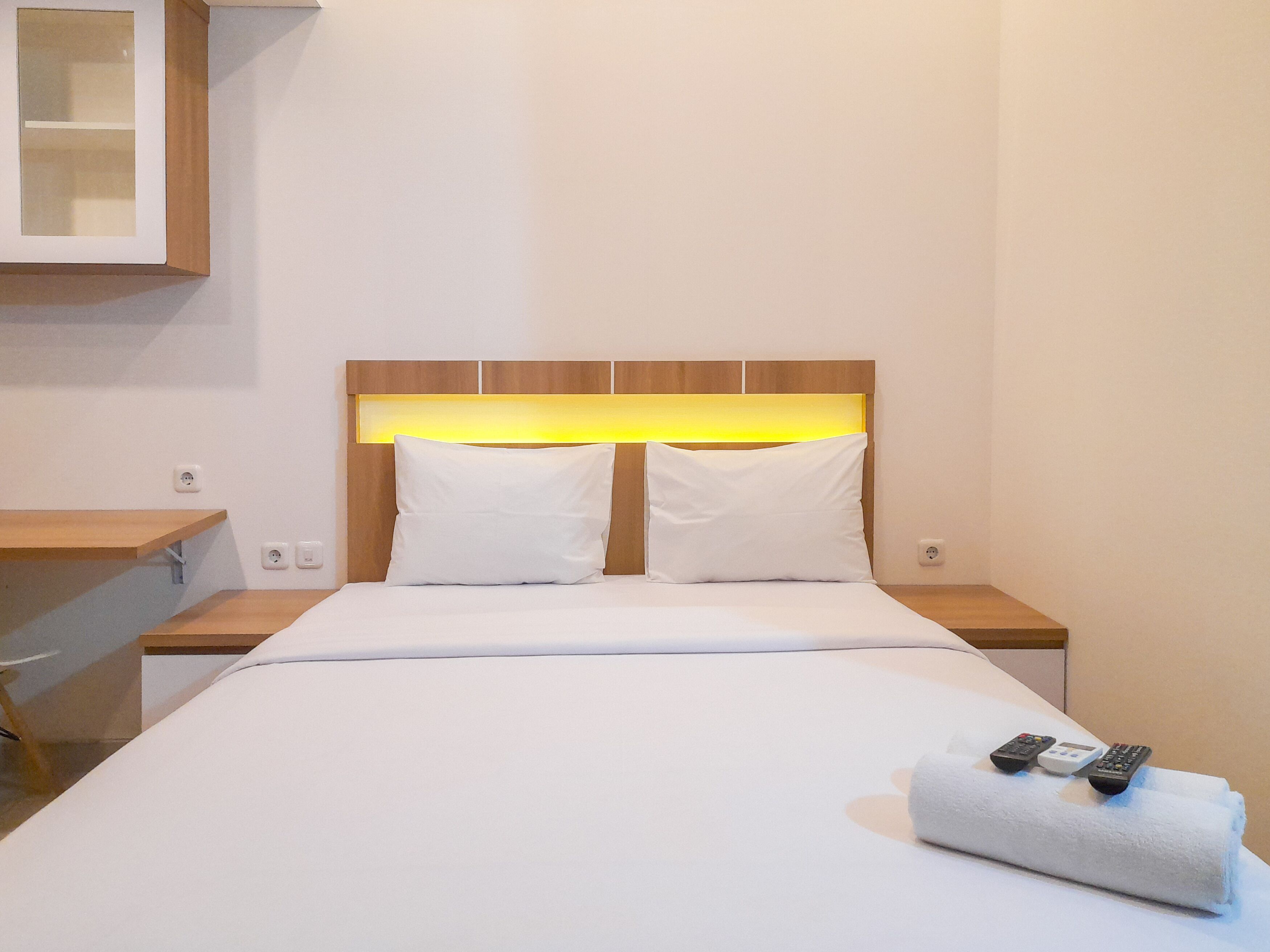 Une chambre d’hôtel avec un lit, deux tables de chevet, une petite table et une lampe.