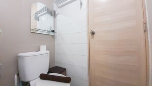 A small bathroom with a toilet, a mirror, and a wooden door. - Relaxing Studio At Taman Melati Sinduadi Apartment (Pogung Lor)