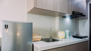 A modern kitchen with a stainless steel refrigerator, a sink, and a kettle.