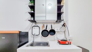Une cuisine équipée d’un évier, d’un réfrigérateur et d’un plan de travail sur lequel se trouvent une machine à café et une bouilloire.