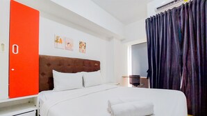 Une chambre d’hôtel avec un lit, une porte rouge, un mur blanc et une fenêtre avec des rideaux.