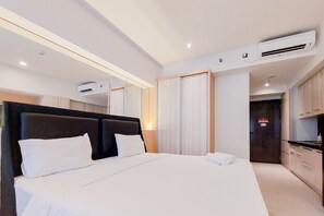 Une chambre d’hôtel moderne avec un grand lit, une tête de lit sombre et un système de climatisation intégré.