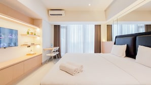 Ein Hotelzimmer mit einem großen Bett, einem Schreibtisch mit Stuhl, einem an der Wand befestigten Fernseher und einem Fenster mit Vorhängen.