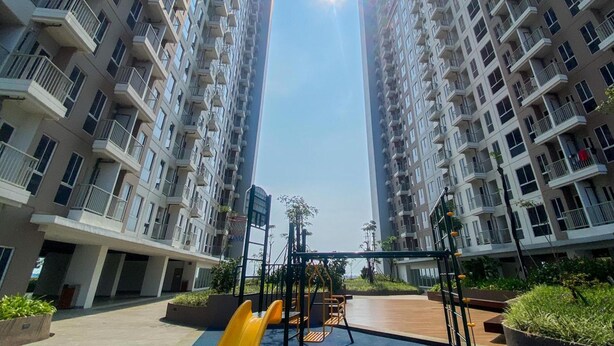 A residential building with multiple balconies and a playground area with slides and swings. - Spacious And Homey 1Br Tokyo Riverside Pik 2 Apartment (Teluknaga)