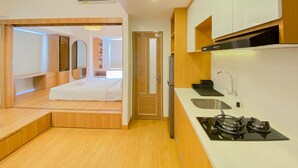 A compact kitchen with a stove, sink, and wooden cabinetry. - Spacious And Homey 1Br Tokyo Riverside Pik 2 Apartment (Teluknaga)