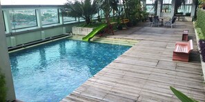An indoor swimming pool with a slide, wooden deck, and outdoor seating area.