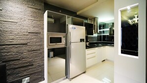 A modern kitchen with a built-in microwave, stainless steel refrigerator, and black countertops. - Spacious And Comfy 2Br Apartment At Aryaduta Residence Surabaya (Surabaya)