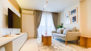 A modern living room with a flat-screen TV, a sofa, a coffee table, and a large window with curtains. - Best Deal And Strategic 2Br Marquis De Lafayette Apartment (Semarang)
