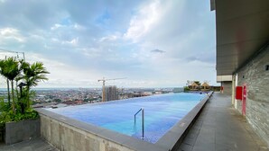 A rooftop infinity pool with a city view, surrounded by a stone deck and a modern building. - Best Deal And Strategic 2Br Marquis De Lafayette Apartment (Semarang)