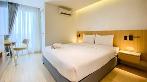 A hotel room with a large bed, a desk, a chair, and a nightstand. - Best Deal And Strategic 2Br Marquis De Lafayette Apartment (Semarang)