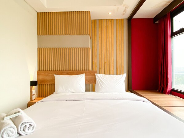 Habitación de hotel con una cama grande, cabecera de madera y vistas a la ciudad desde la ventana.