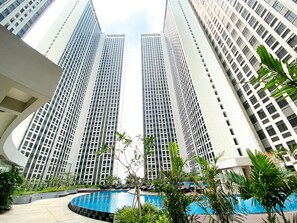 Un moderno edificio de gran altura con un área de piscina rodeada de vegetación.