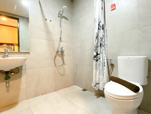 Un baño con lavabo, inodoro, ducha y una toalla colgada en la pared.