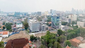 Une vue urbaine présentant divers bâtiments, dont un immeuble moderne remarquable avec un design original et un bâtiment traditionnel doté d’un toit rouge.