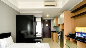 Une chambre d’hôtel équipée d’un lit, d’une télévision, d’un coin cuisine et d’un appareil de climatisation.