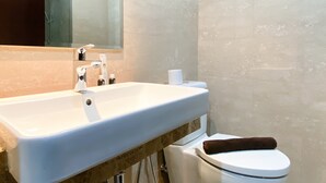 Une salle de bain avec un lavabo blanc, un miroir et des toilettes.