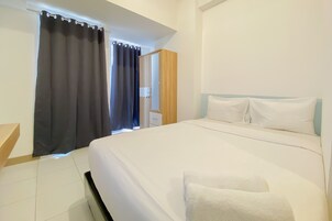 Uma cama bem arrumada com lençóis brancos, um guarda-roupa de madeira e uma mesa de cabeceira branca.