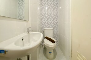 A bathroom with a white sink, toilet, and tiled walls.