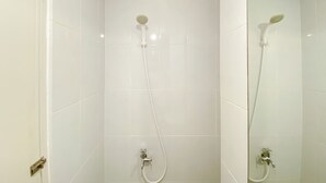 A bathroom with white tiled walls and a shower with a handheld showerhead and a wall-mounted faucet. - Fully Furnished And Modern Studio At Tokyo Riverside Apartment Pik 2 (Teluknaga)