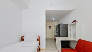 A small, clean room with a bed, a red sofa, a white desk, and a refrigerator. - Cozy Stay Studio Apartment At M-Town Residence (Gading Serpong)