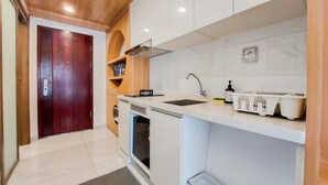 A modern kitchen with white cabinets, a stainless steel sink, and a built-in oven. - Minimalist Studio At Sky House Alam Sutera Apartment (Tangerang)