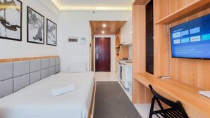 A hotel room with a bed, a desk, a TV, and artwork on the wall. - Minimalist Studio At Sky House Alam Sutera Apartment (Tangerang)