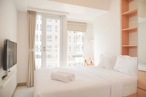 Ein Hotelzimmer mit einem Bett, einem Fernseher, einem Fenster mit Vorhängen und Blick auf Gebäude.