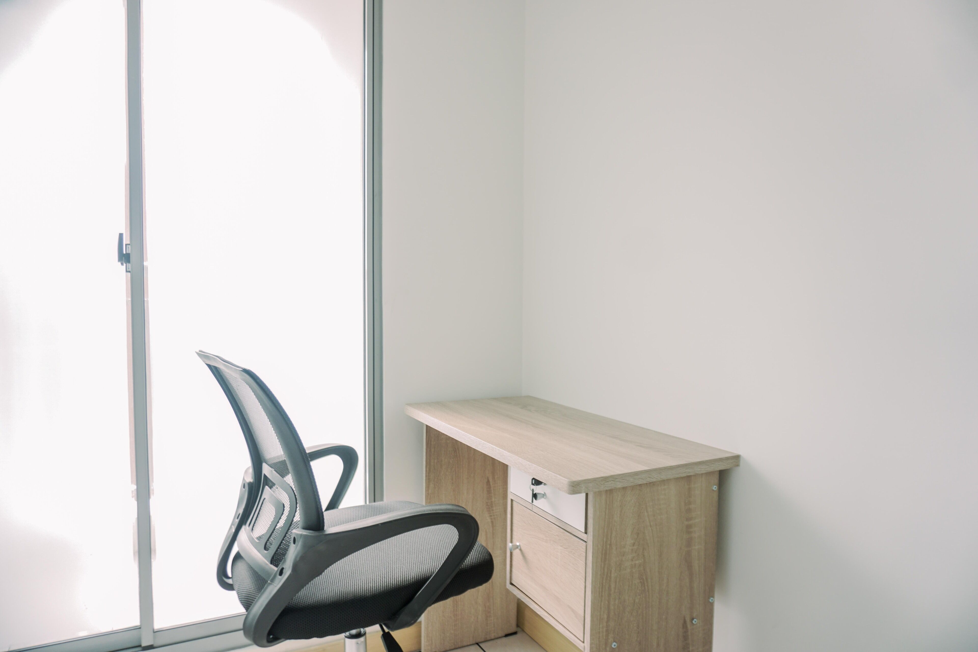 A corner office with a desk, chair, and a sliding door.