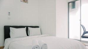 A neatly made bed with white linens and rolled towels, a black headboard, and a large window with a view of the outdoors. - Good Choice 2Br Apartment M-Town Residence (Gading Serpong)