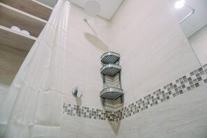 Une douche avec un rideau blanc et un mur carrelé.