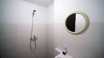 A bathroom with a shower, a toilet, and a round mirror on the wall.