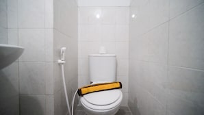 A small, white bathroom with a toilet, a white sink, and a shower area. - Simple And Tidy Studio Apartment At Suncity Residence (Sidoarjo)