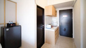 A compact kitchen with a refrigerator, a sink, and a countertop. - Simple And Tidy Studio Apartment At Suncity Residence (Sidoarjo)