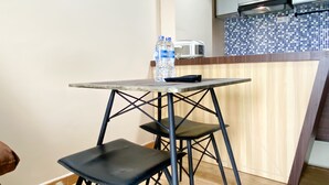 A small kitchenette with a tiled backsplash, a microwave, and a water dispenser on a wooden table. - Best Deal And Homey 1Br Apartment Grand Sentraland Karawang (Karawang)