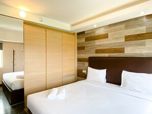 Una habitación de hotel moderna con una cama grande, un armario de madera y una pared con paneles de madera.