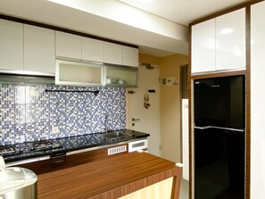 Una cocina moderna con un refrigerador negro, armarios blancos y un salpicadero de azulejos azules.