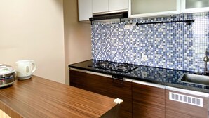 A kitchen with a tiled backsplash, a stove, a sink, and wooden cabinets. - Best Deal And Homey 1Br Apartment Grand Sentraland Karawang (Karawang)